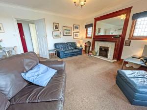 a living room with a leather couch and a fireplace at Plover Apartment - Uk51129 in Carradale
