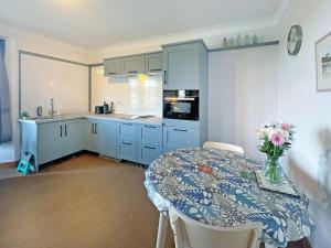 a kitchen with blue cabinets and a table with flowers on it at Plover Apartment - Uk51129 in Carradale