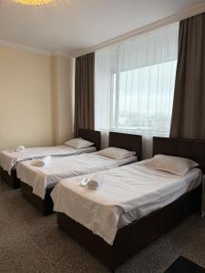 three beds in a room with a window at Family Hotel in Batumi