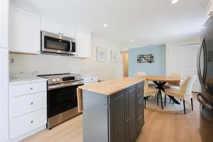 a kitchen with white cabinets and a wooden table at Prime Weeks Still Available, Renovated, Beaches! in Yarmouth
