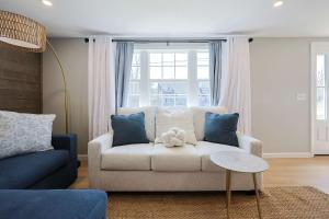 a living room with a white couch and blue pillows at Prime Weeks Still Available, Renovated, Beaches! in Yarmouth