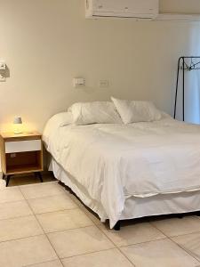 a bedroom with a white bed and a night stand at Verde Limon Loft (monoambiente) in San Salvador de Jujuy +21 photos