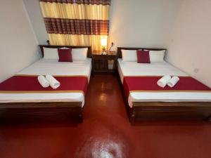 two beds in a room with red and white pillows at The Red Loft Mihinthale in Anuradhapura