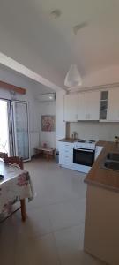 a kitchen with white cabinets and a stove top oven at Kate House in Agioi Apostoli