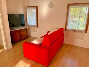 a red couch in a living room with a television at Ca' Luciana Valdobbiadene in Valdobbiadene