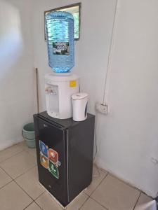 a small refrigerator with a water bucket on top of it at Avery's Cottage in Livingstone