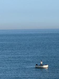 a man in a boat in the middle of the ocean at Bukowski Loft House in Porticello
