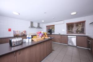 a large kitchen with wooden cabinets and a counter top at ibis Budget Perth Airport in Perth