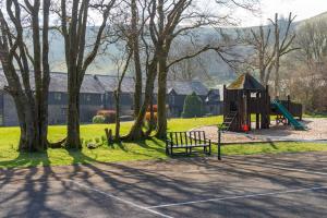 a park with a playground with a bench and trees at Lake Cottages at Cwm Chwefru in Llanafan-fawr