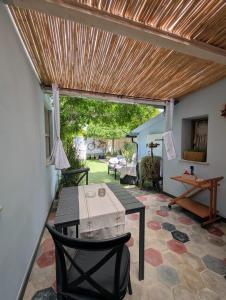 a patio with a table and chairs and a wooden ceiling at La casa del glicine Marrubiu in Marrùbiu