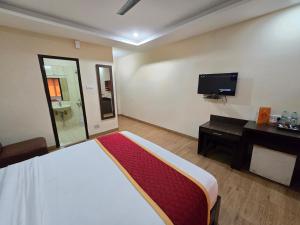 a bedroom with a bed and a desk and a television at Hotel Ashok Residency, Porur in Chennai
