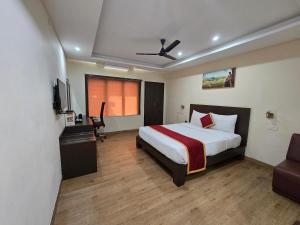a bedroom with a bed and a television and a couch at Hotel Ashok Residency, Porur in Chennai