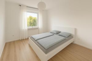 a white bedroom with a bed and a window at Pulheim Living 6 in Pulheim
