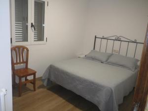 a bedroom with a bed and a chair and a window at Hotel Del Llac in Coll de Nargó