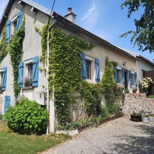 an ivy covered building with windows and doors at Chambre d'hôte Le Châtaignier in Planchez