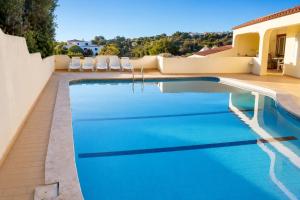 a swimming pool in a backyard with chairs and a house at Casa Nuno in Lagoa +3 photos