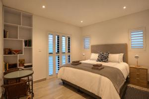 a bedroom with a bed and a table and windows at Yzer4You in Yzerfontein