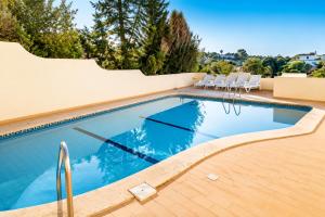 a swimming pool with chairs next to a house at Casa Nuno in Lagoa