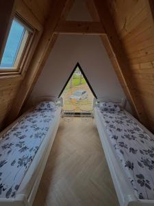 two beds in a attic room with a window at Vlasic Odmor - Villa Ajla in Vlasic