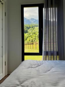 ein Schlafzimmer mit Bett und Fenster mit Aussicht in der Unterkunft Peak View Tiny House - Piatra Craiului Nest in Zărneşti