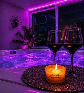 two glasses of wine and a candle on a table at Luxor - Private Jacuzzi Boulevard Suites in Sibiu