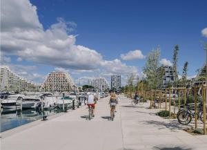 two people riding bikes down a sidewalk next to a marina at 100m de la plage in La Grande Motte