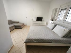 a bedroom with a bed and a couch and a television at KONSTANTINOS Luxury Living in Ofrínion
