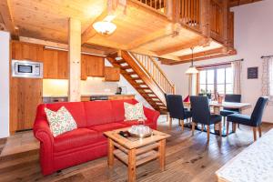 a living room with a red couch and a table at Loderbichl Alm Ferienwohnungen in Lofer