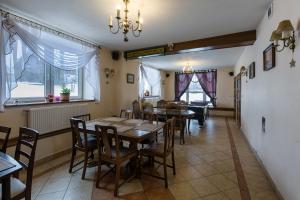 a dining room with tables and chairs and windows at Willa Natia in Kluszkowce