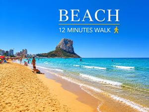a beach with people walking on the sand and the ocean at Luxury Villa Galaxy Beach 12min walk 15m pool in Calpe