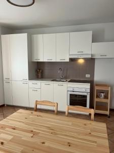 a kitchen with white cabinets and a wooden floor at Al Monte Zelo in Agordo