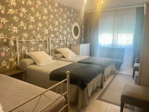 a bedroom with two beds with floral wallpaper at Viviendas Uso Turístico Arzúa in Arzúa