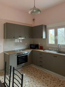 a kitchen with gray cabinets and a sink and a microwave at Morpheas Apartment in Central Myrina in Myrina
