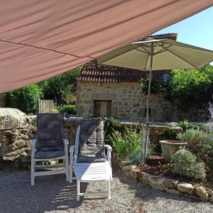 two chairs sitting under an umbrella in a garden at La Maison des 2L in Saint-Médard