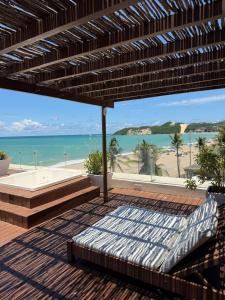 a patio with a bed and a view of the beach at Elegance Comfort Natal Beira mar Coberturas Vip in Natal