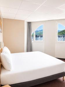 a white bed in a room with two windows at Hotel Saint Georges Lourdes in Lourdes +65 photos