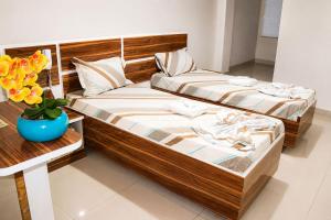 two beds in a room with a vase of flowers at GM Hotel SP in Utinga