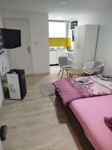 a bedroom with a pink bed and a kitchen at Apartman Deni in Tuzla