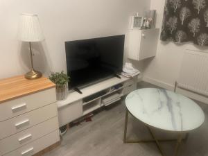 a living room with a flat screen tv and a glass table at Room Younis in Tilehurst