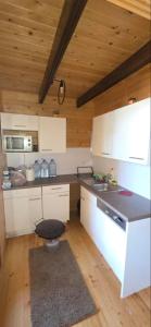 a kitchen with white cabinets and a black stool at Sunshine House Ada Bojana in Ulcinj