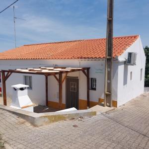 a small white building with a large roof at Casinha Serrinha in Mértola