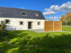 a white house with a wooden fence in front of it at Maisonnette cosy proche de la côte in Lesneven