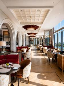 a restaurant with tables and chairs and windows at Raffles Jeddah in Jeddah