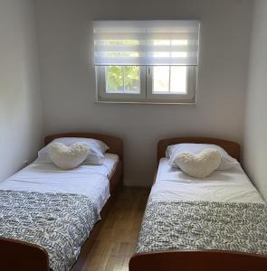 two beds in a room with hearts shaped pillows on them at Vecky in Jezera