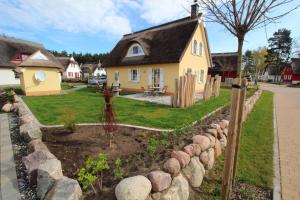 einen Garten vor einem gelben Haus in der Unterkunft Reethaus Seeschwalbe in Glowe