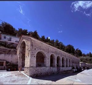 a stone bridge with arches on the side of a building at George's house samos in Pagóndas