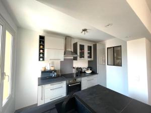a kitchen with white cabinets and a black counter top at VERLAINE House in Menton +5 photos