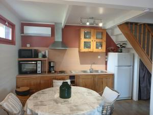 a kitchen with a table and a white refrigerator at Le Chalet de Gonnehem in Gonnehem