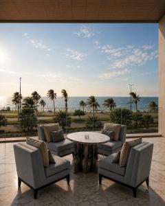 a living room with a table and chairs and the ocean at Raffles Jeddah in Jeddah