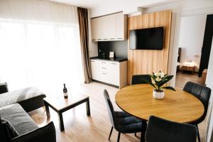 a living room with a wooden table and a kitchen at Riverside ApartHotel by InnTime in Cluj-Napoca
